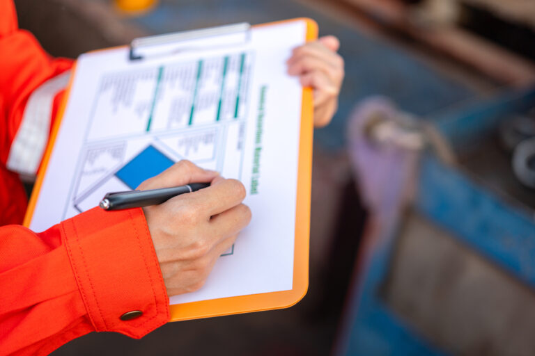 Action of a supervisor is using a pen to writing on chemical hazardous material paper form to rating the risk. Industrial safety working. Selective focus.